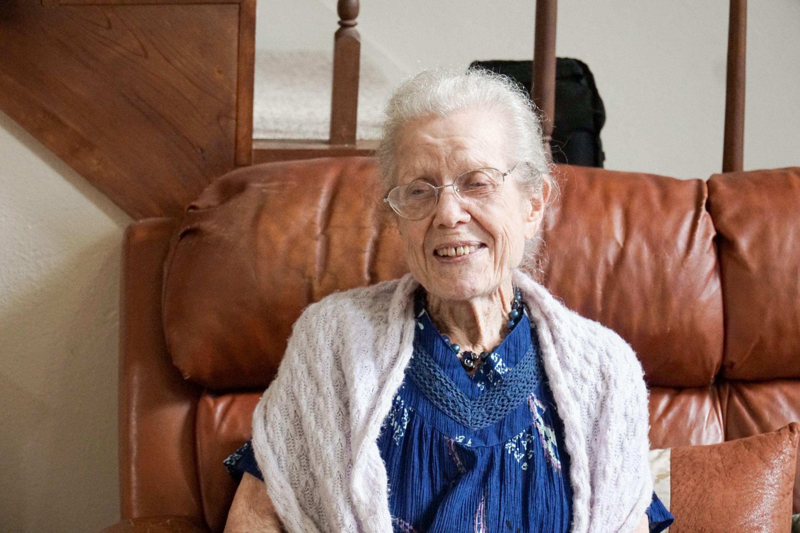 an elderly white woman sitting on a recliner and wearing a cardigan.