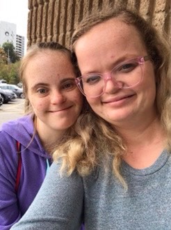 Chantel and Naomi are white young adult females with blond hair. Chantel has visible signs of an intellectual disability and Naomi wears glasses.