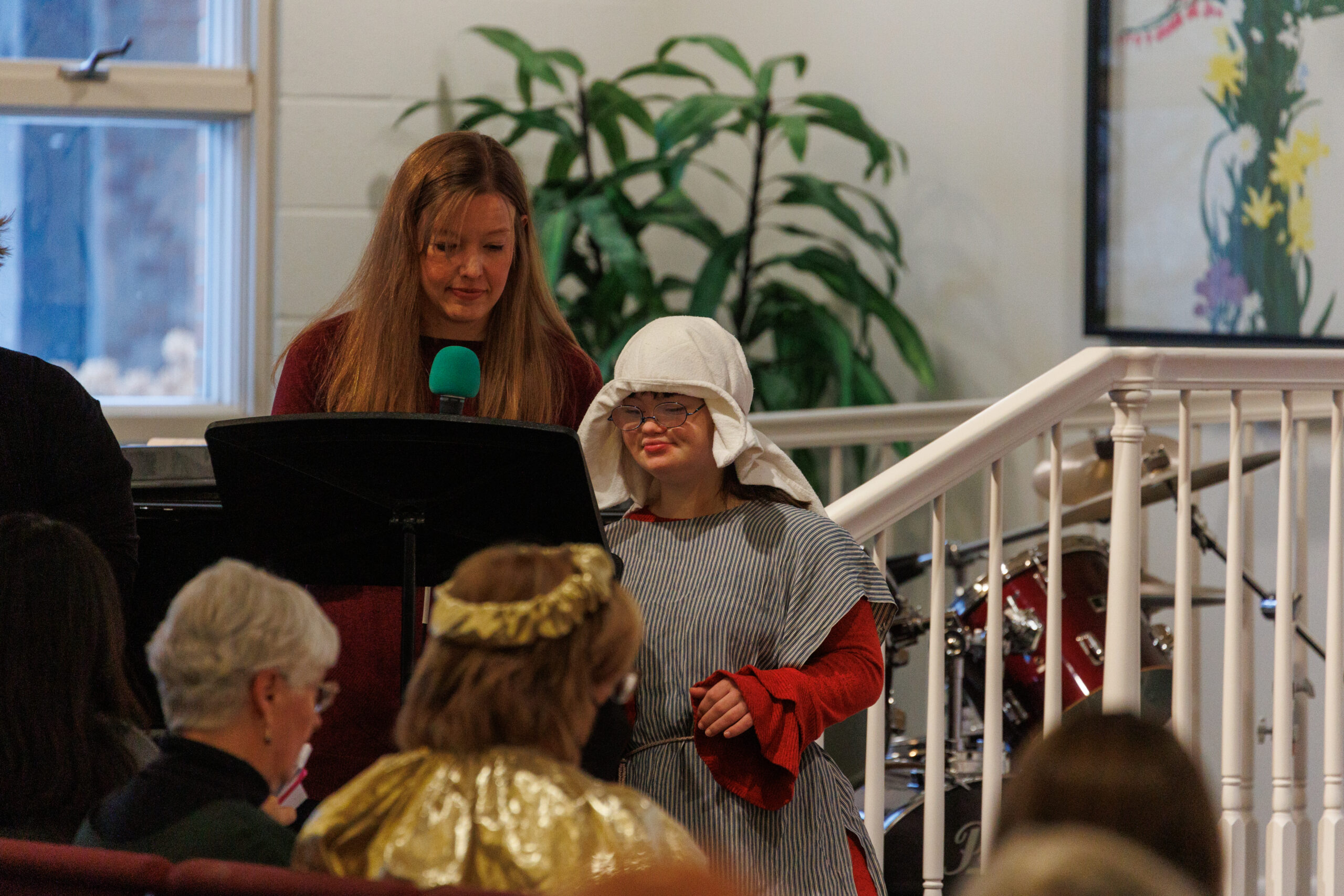 a teenager with down syndrome and an adult without visible disabilities speak during a church service.