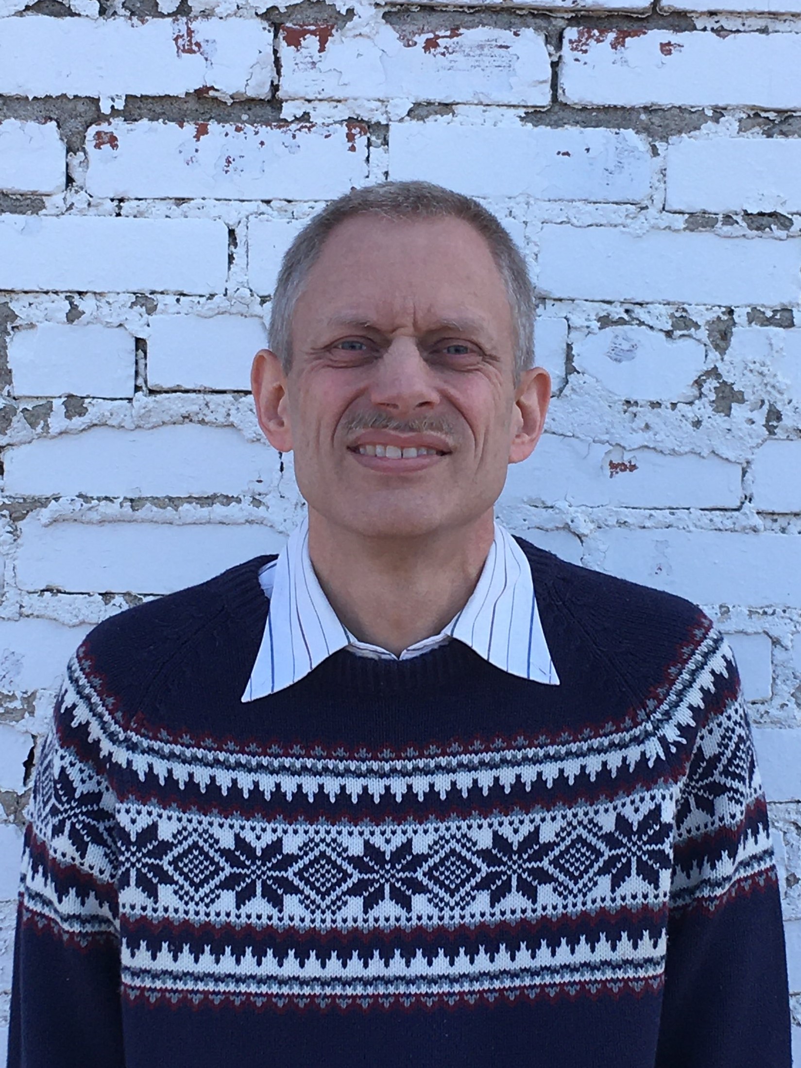 Christopher Stoltzfus is a middle-aged white male with a graying mustache wearing a sweater.