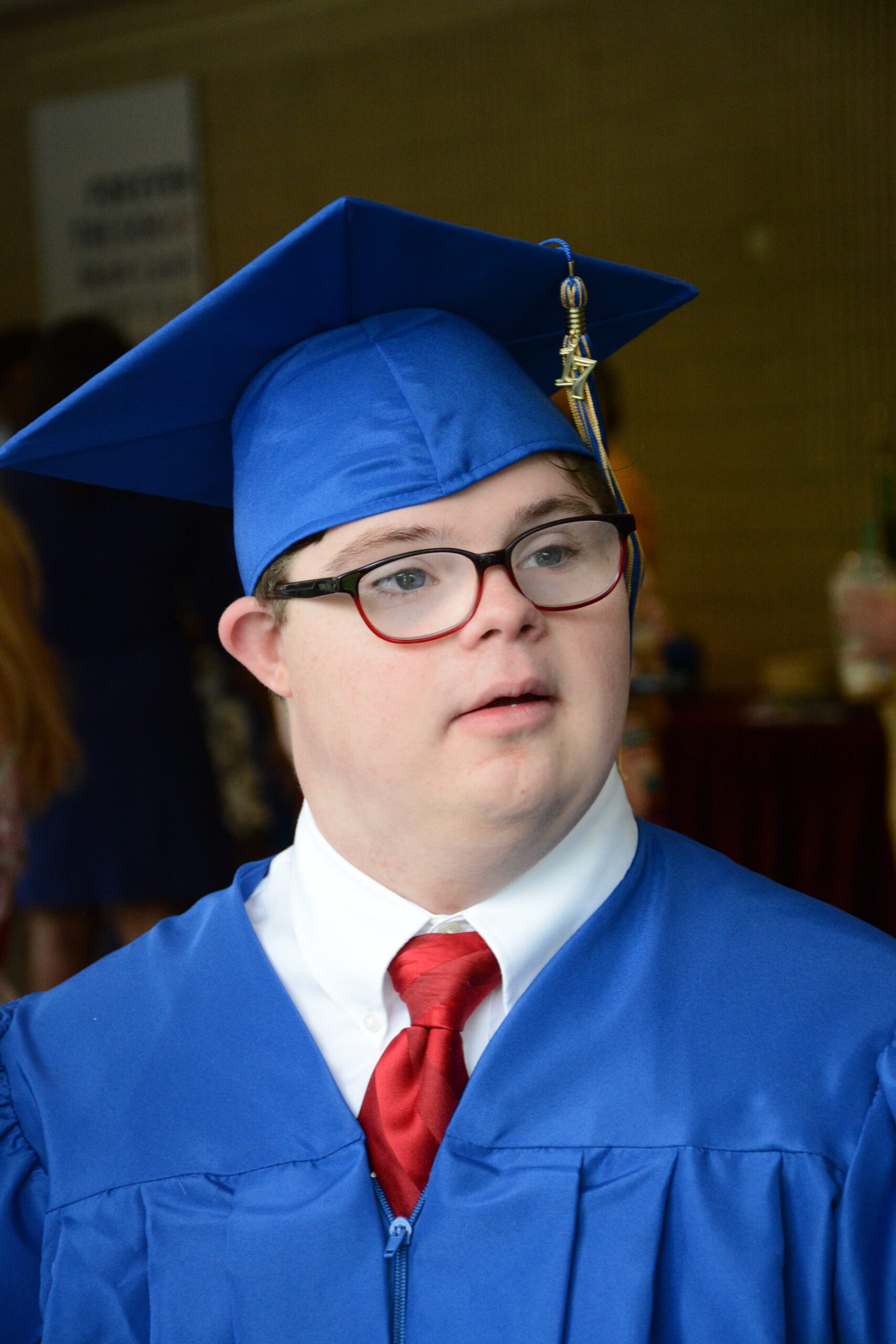 young white adult male with down syndrome wearing a cap and gown