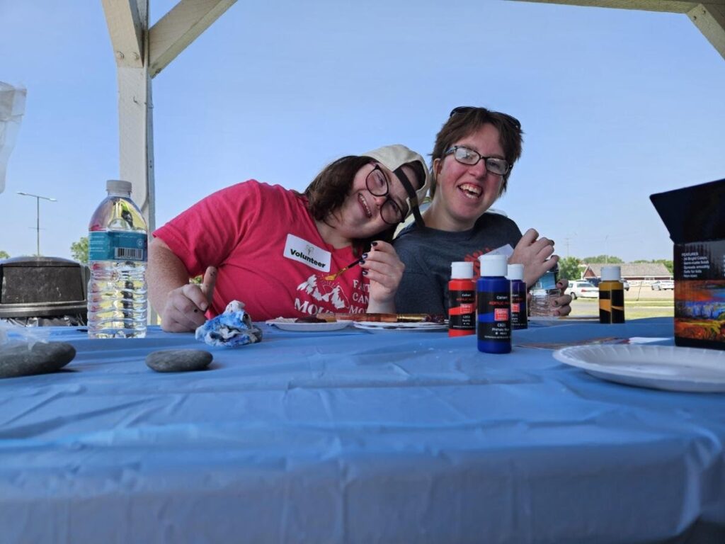 two white female young adults with signs of intellectual disabilities smile together.