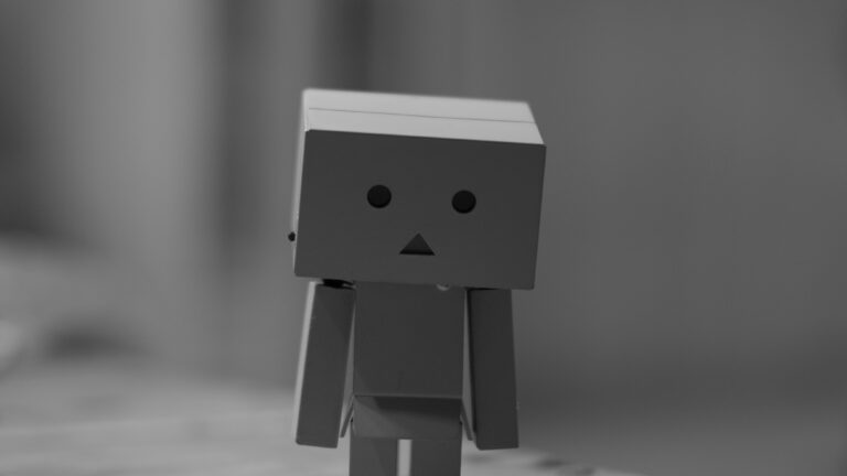 a humanoid figure made out of cardboard boxes with a sad face drawn on its head.