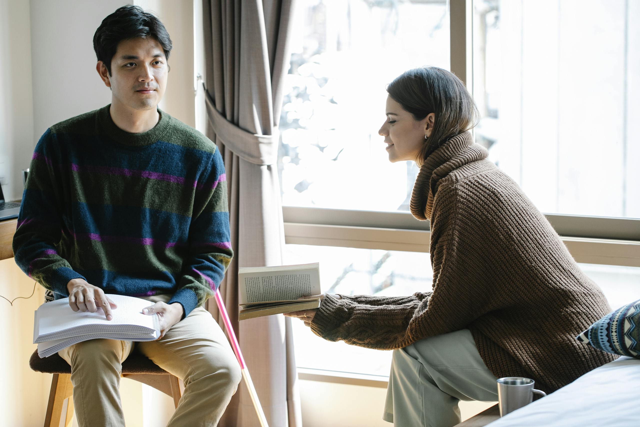 A man reads using a braille note and a woman reads using a book.