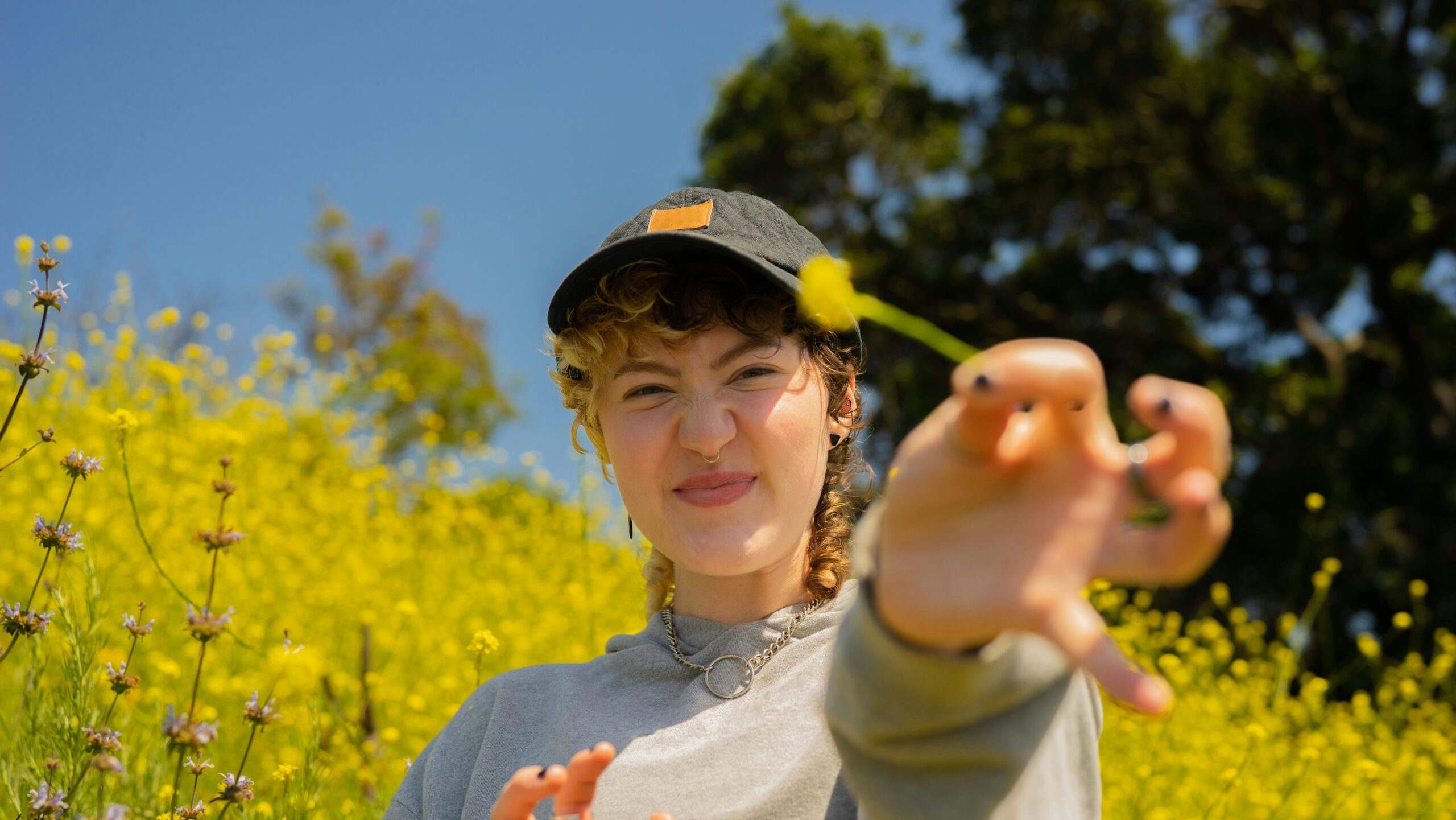 a white, nonbinary young adult with autism holding a flower outside