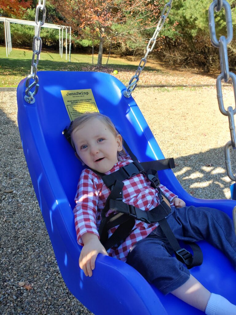 a small white child in a Jenny Swing