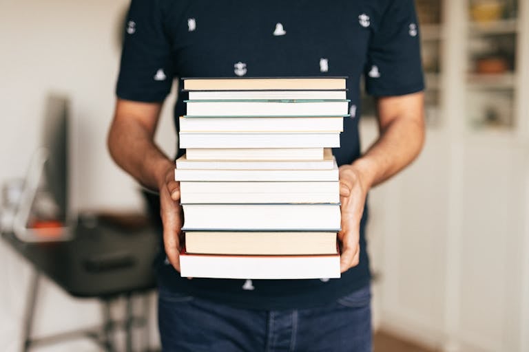 Person Carrying a Stack of Books