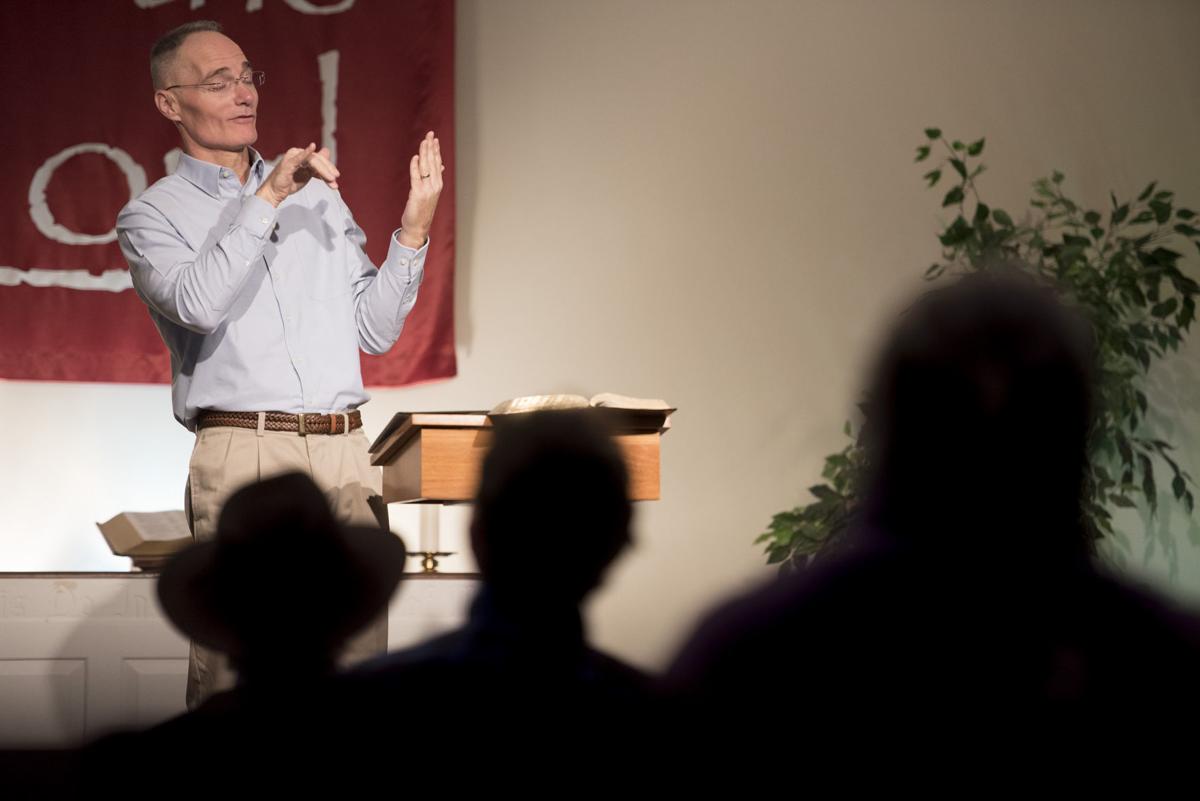 a middle-aged white man uses sign language to preach a sermon.