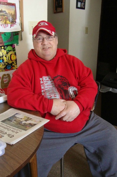 Kent is a middle-aged white man wearing Goshen High School Athletics sweatshirt and hat.