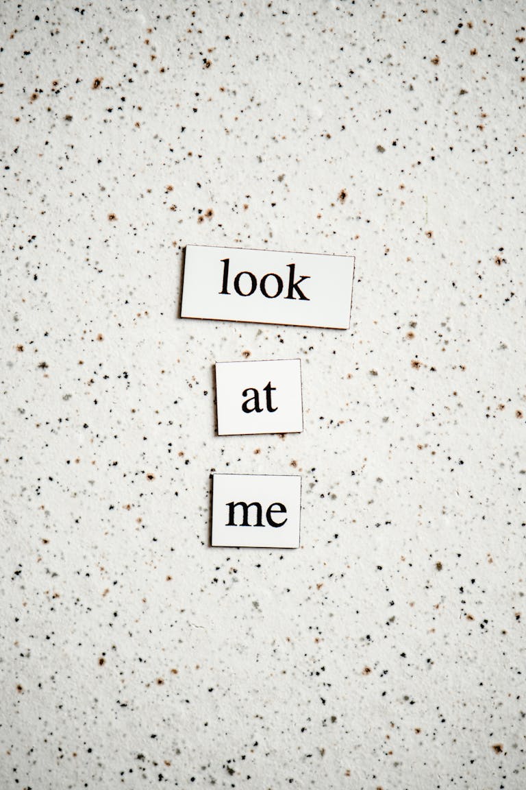 Minimalist text design with "look at me" on speckled surface.